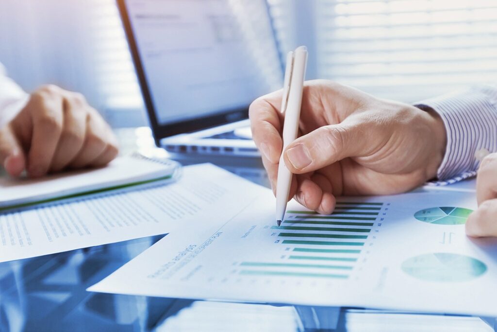 Hand holding a pen and marking up paper reports